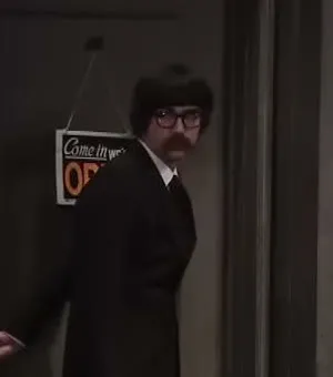 As Bank teller in Shoulder Angel (Studio C, 2012). Documented scene-context crop from the official source; StarMapr abstained.